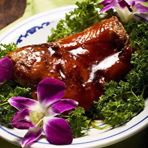 San bei ya duck, traditional hakka cuisine garnished with fresh parsley and pink orchard flowers on platter in Chinese restaurant, close up