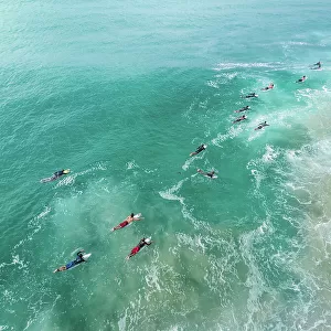 Aerial shot showing surfers paddling out to the waves on the Coral Sea, Gold Coast, Queensland, Australia