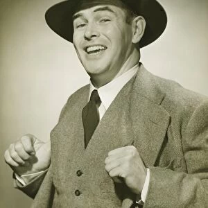 Businessman holding thumbs in waistcoat, smiling, (B&W), portrait