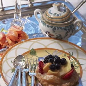 Fruit tart on a decorative plate with silver cutlery and a stylish ambience