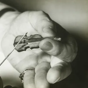 Man holding tiny violin, close up of hands