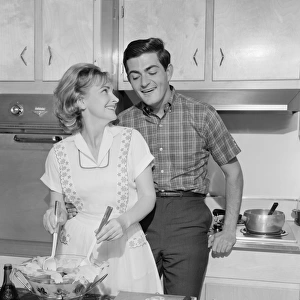 Mid adult couple in kitchen, woman preparing salad