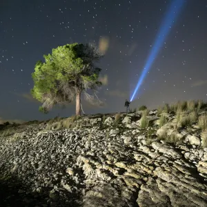 Person lighting the sky with a flashlight