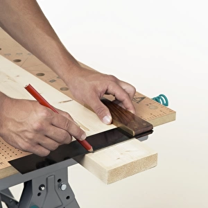 Person marking line on wood against square
