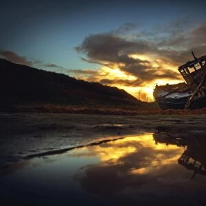 Shipwreck on beach at sunset