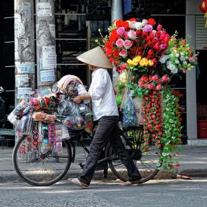 A street vendor with a bicycle selling her flowers in Hanoi, Vietnam, Asia