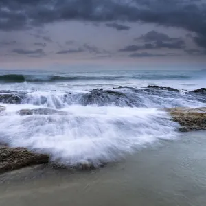 Wave jumping rocks in storms at sea at dawn