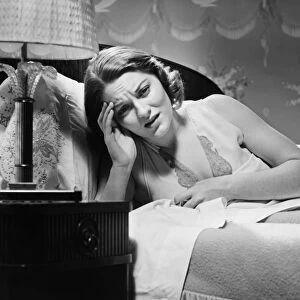 Woman suffering headache lying in bed (B&W)