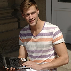 Young man with laptop sitting on steps