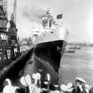 Cheering sailors of HMS Indomitable, the aircraft carrier, raise their hats in salute