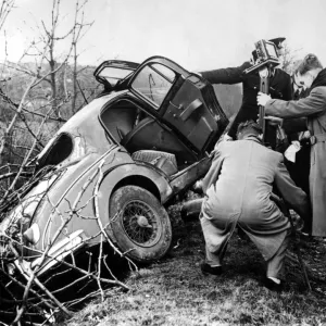 Police and photorgraphers are seen with the wreck of the black Jaguar car in which