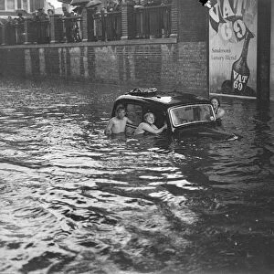 Swimmers around submerged vehicles in the greatest recorded floods in Kingston, the