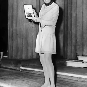 A photograph print of Mary Quant holding the Order of the British Empire medal A photograph print of Mary Quant holding the Order of the British Empire medal