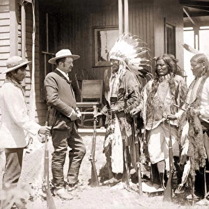 Three Cheyenne dressed in ceremonial costume and wearing guns greet a White accompanied