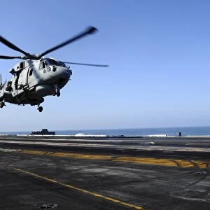 Airman directs an EH-101 Merlin helicopter onto the flight deck of USS John C. Stennis