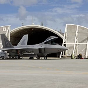 An F-22 Raptor parked in front of a hardened aircraft shelter at Kadena Air Base