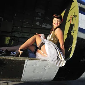 Sexy 1940s style pin-up girl sitting inside of a C-47 Skytrain aircraft