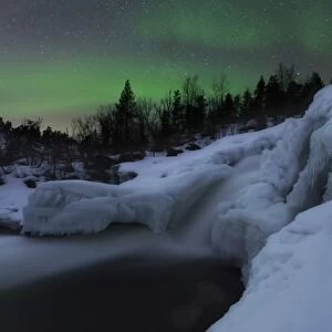 A wintery waterfall and aurora borealis over Tennevik River, Norway