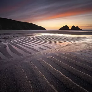 Holywell Bay at low tide, ripples and reflections at sunset, looking towards Carter's Rocks, Holywell Bay, near Newquay, Cornwall, UK. March 2021