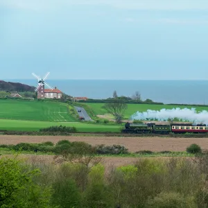 Steam train on the Heritage Poppy Line from Sheringham to Holt, with Weybourne Mill in background