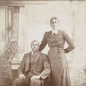 Photograph of a man sitting down with a woman standing next to him, 1880s - 1900