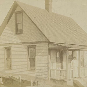 Photograph of a woman standing on the porch of a house, early 20th century