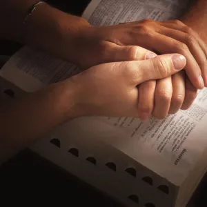 Holding Hands And Praying Over The Bible