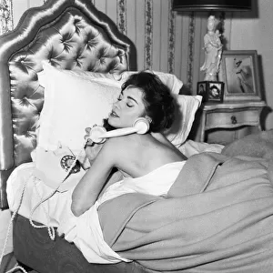 Actress Jackie Lane lying in bed naked talking on the telephone March 1959