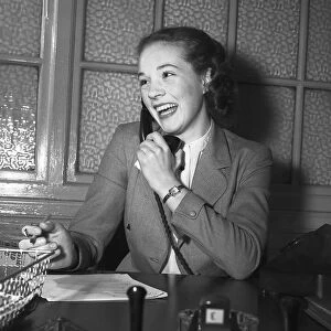 Actress Julie Andrews talking on the phone behind her desk January 1954