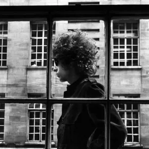 American singer Bob Dylan pictured walking past a shop window during his visit to London