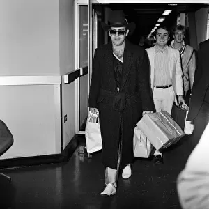 The arrival of Elton John at Heathrow Airport carrying Christmas presents from a buying