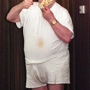 Bernard Manning comedian eating a Walls Arctic Roll dessert. September 1997