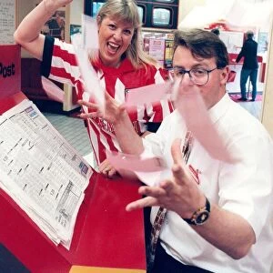 A bookie and a cashier in a betting shop with some winning tickets in April 1996