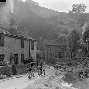 Two boys out on their bicycles near a stream in the Peak District village of Castletown