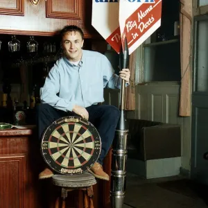 Chelsea and England footballer Dennis Wise poses in a public house with a dartboard