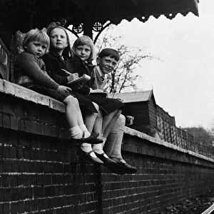 Children sitting on a wall looking at trains arriving and departing from Barnwell