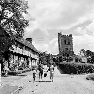 A family walk down the street in the village of Long Crendon, Buckinghamshire