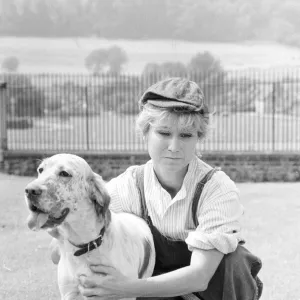 Felicity Kendal dressed as a gardener with a dog July 1982 whilst filming a new