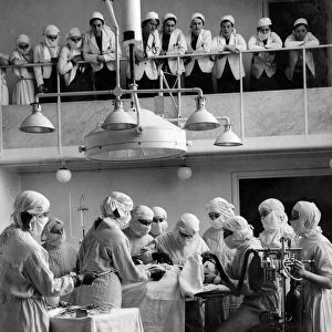 A female surgeon operating, watched by students, at the Royal Free Hospital
