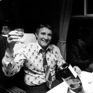 Football manager Malcolm Allison drinking champagne n the train