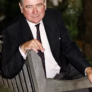 George Baker actor sitting on park bench