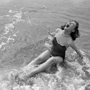 A girl screams out as she sits down in the cold water during a visit to the beach in