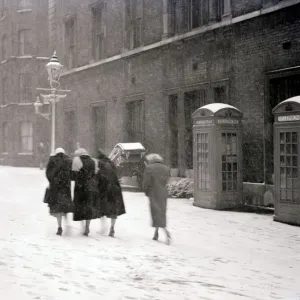 A group of women make their way up the street through the heavy snow past a row of