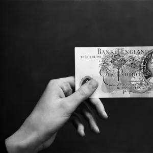 A hand holding a pound note. 14th February 1974