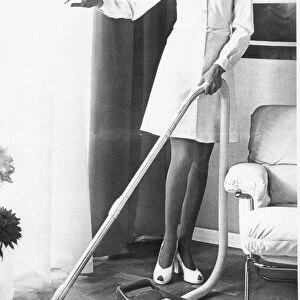 A housewife spring cleaning her lounge with a vacuum cleaner