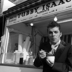 Ian Dury outside the East End stall of Tubby Isaacs eating bowl of Jellied eels