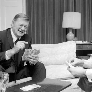 John Wayne pictured relaxing playing cards in his suite at The Connaught Hotel, Mayfair