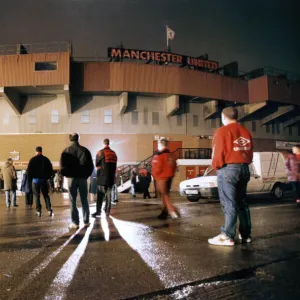 Manchester United fans bow their heads in respect during a slient vigil outside Old