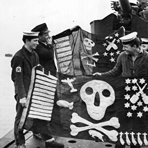 Members of HMS Torbays crew with the ships Jolly Rogers of success