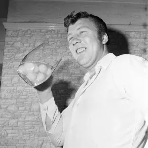 A 1969 photograph print of a man eating raw eggs A 1969 photograph print of a man eating raw eggs